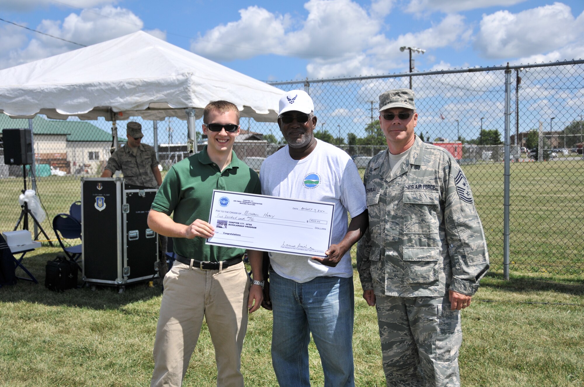 The Niagara Chief's Group and Air Force Sergeants Association scholarship winner Michael Healy being given his big check by Command Chief Master Sgt. Scott Scharlau during the 914th Family Day event August 7, 2010, Niagara Falls Air Reserve Station, NY. Healy won his scholarship by writing a 500 word essay on the topic "How has Air Force humanitarian missions changed from the Berlin Airlift to today". (U.S. Air Force photo by Staff Sgt. Joseph McKee)