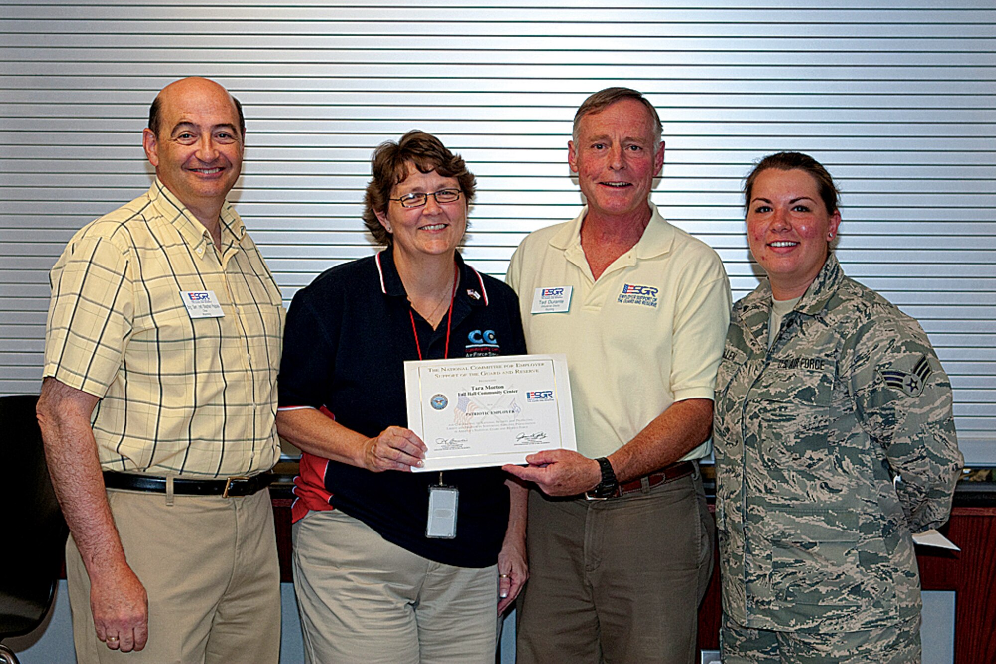 Brig. Gen. (ret) Stephan Pappas, Ted Durante, 90th Civil Engineer Squadron, and Senior Airman Misty McMullen, 90th Forces Support Squadron, present Tara Morton, 90th FSS, with the Employer Support of the Guard and Reserve Patriot Award on July 20 in the Fall Hall Community Center. (U.S. Air Force photo by Jeff Allred)