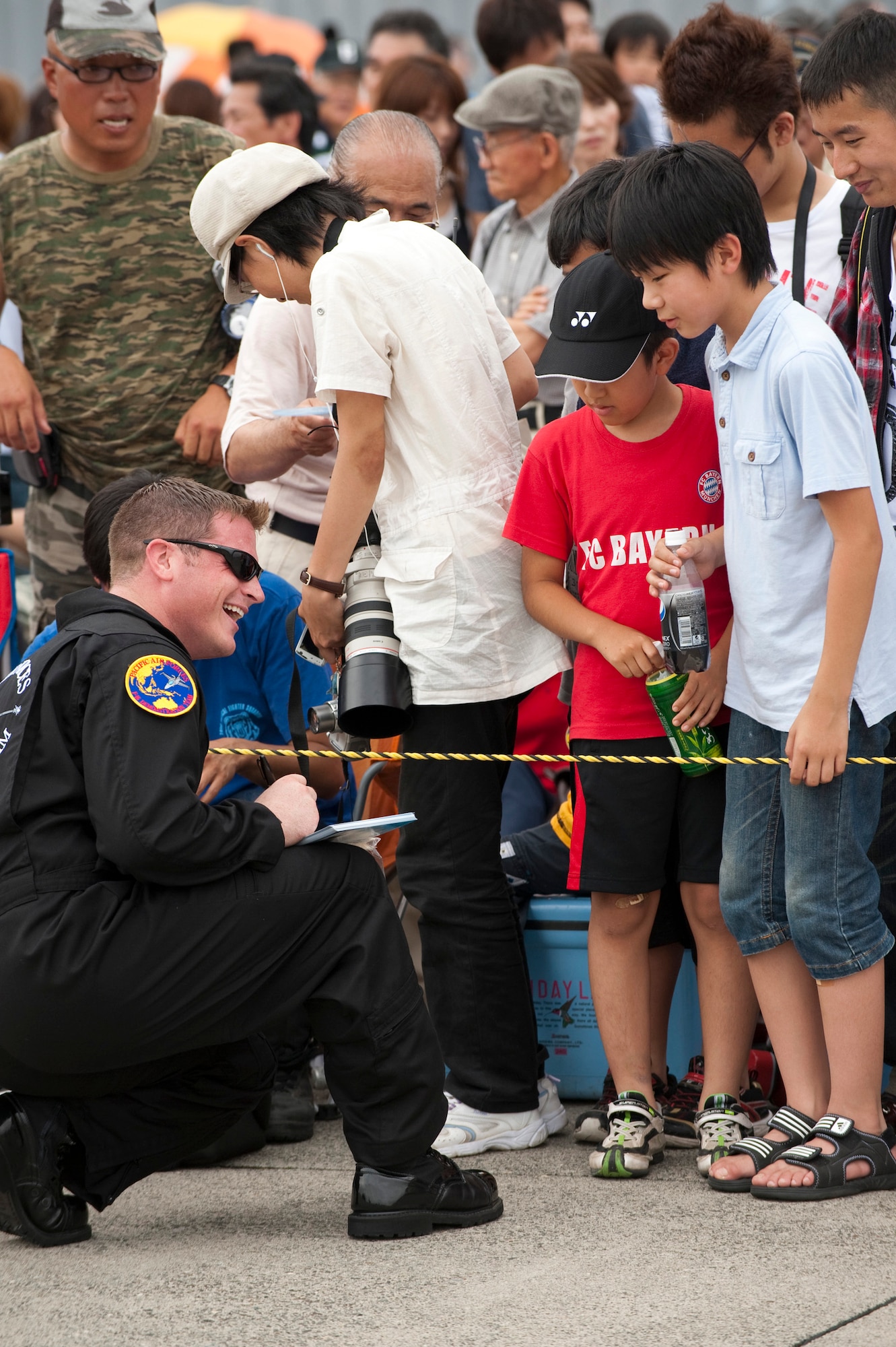 CHITOSE AIR BASE, Japan -- Staff Sgt. Chad Miller, Pacific Air Forces Demonstration Team crewchief, signs photos for spectators following a performance at the Chitose Air Festival, Aug. 8. More than 64,000 people showed up despite forecasted rain to see the air festival. (U.S. Air Force photo/Staff Sgt. Samuel Morse)