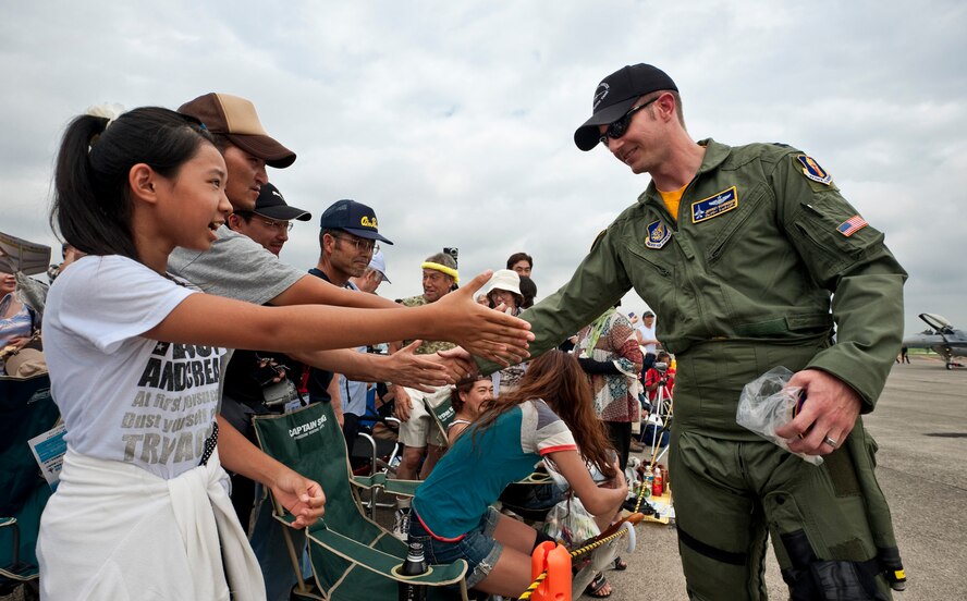 CHITOSE AIR BASE, Japan -- Capt. Jeffrey Schneider, Pacific Air Forces Demonstration Team pilot, shakes hands with spectators following a performance at the Chitose Air Festival, Aug. 8. Captain Schneider performed a low-altitude maneuvering demonstration in an F-16 Fighting Falcon. (U.S. Air Force photo/Staff Sgt. Samuel Morse)