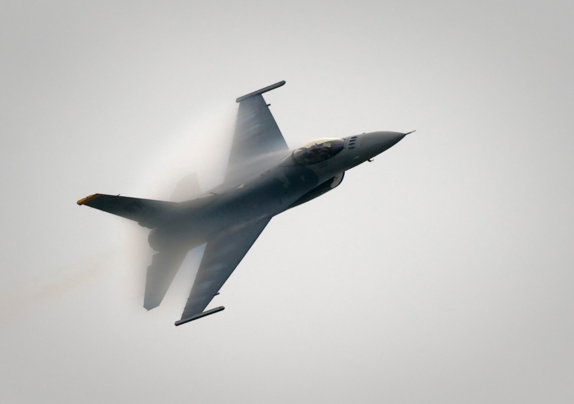 CHITOSE AIR BASE, Japan -- Capt. Jeffrey Schneider, Pacific Air Forces Demonstration Team pilot, performs a dedication pass during the Chitose Air Festival, Aug. 8. The low pressure caused by the turn combined with high humidity caused water to condense behind the wings. (U.S. Air Force photo/Staff Sgt. Samuel Morse)