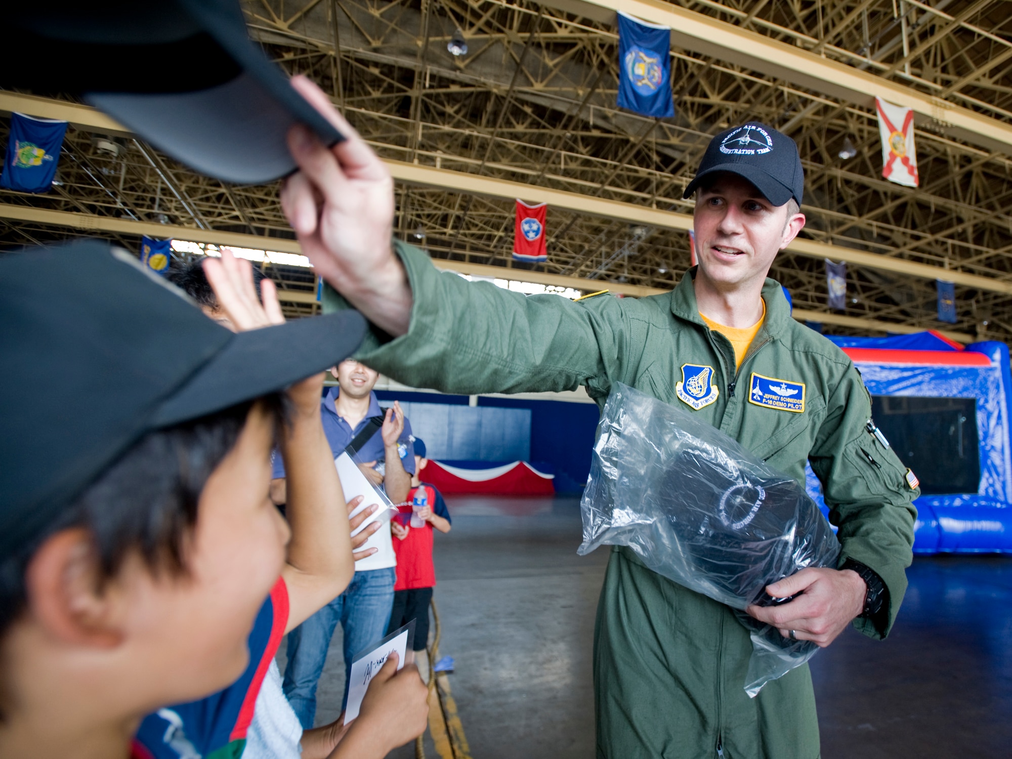 MISAWA AIR BASE, Japan -- Capt. Jeffrey Schneider, Pacific Air Forces F-16 demonstration team pilot, passes out hats to children from the Hirosaki Aiseien orphanage during Friendship Day Aug. 5 at Hangar 949. After observing an F-16 demo, the children were also allowed to take photos with the demo team and jet. Misawa Air Base has interacted with the Hirosaki Aiseien orphanage since 2004. (U.S. Air Force photo/Senior Airman Jamal D. Sutter)