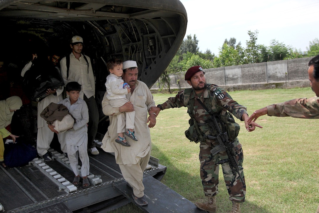 A member of the Pakistani military helps civilians disembark a U.S. Army CH-47 Chinook helicopter during an evacuation mission in Khwazakhela, Pakistan, Aug. 5, 2010.