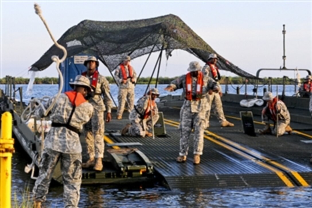 U.S. Army soldiers dock an Improved ribbon bridge to take on heavy machinery to assist in beach cleanup operations on Grand Isle, La., Aug. 8, 2010. The soldiers are assigned to the 2225th Multi-Role Bridge Company, U.S. Army National Guard, based out of Marrero and Slidell, La. The company assists by carrying equipment to sites that need supplies and offloading soiled materials from cleanup sites.