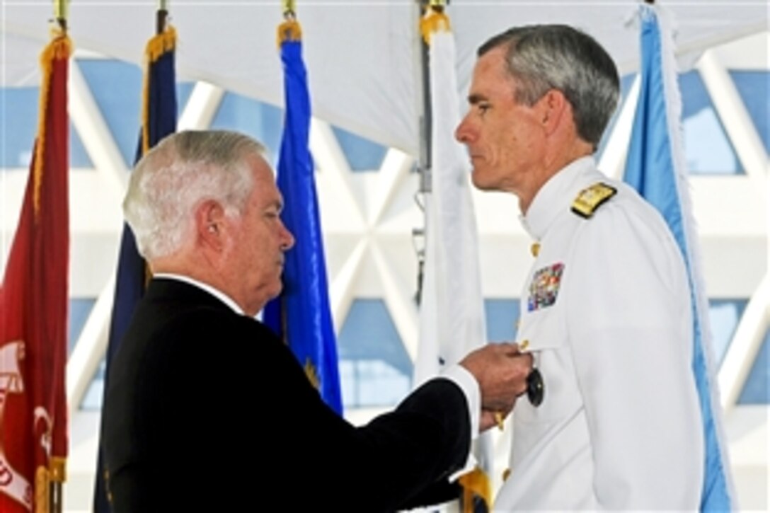 Defense Secretary Robert M. Gates presents an award to Navy Vice Adm. Robert B. Murrett, outgoing director of the National Geospatial-Intelligence Agency, during a ceremony to mark the changing of directors at the agency's new east campus in Springfield, Va., Aug. 9, 2010. Murrett relinquished command to Letitia Long, the first female to head a U.S. intelligence agency.