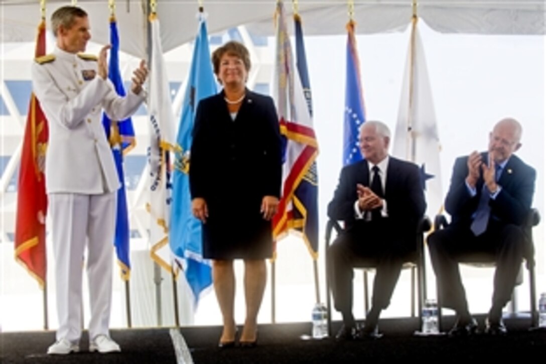 Letitia Long, the incoming director of the National Geospatial-Intelligence Agency, smiles as Navy Vice Adm. Robert B. Murrett, outgoing director, left, Defense Secretary Robert M. Gates, second from right, and James R. Clapper Jr., the director of national intelligence, right, applaud during a ceremony to mark the changing of directors at the agency's new east campus in Springfield, Va., Aug. 9, 2010.