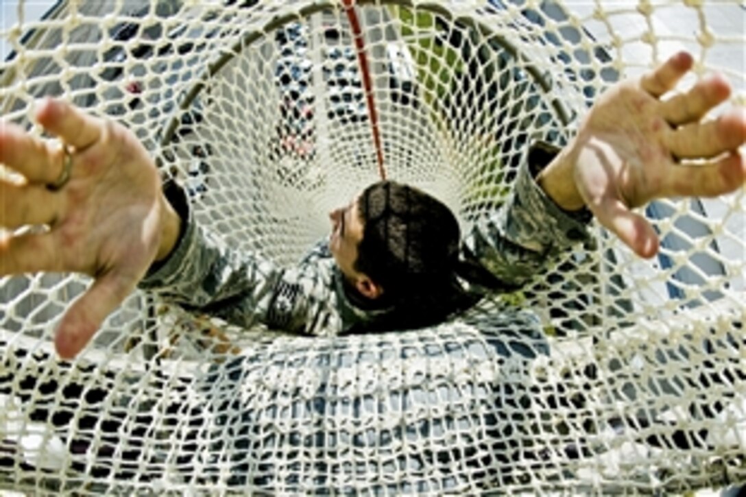 U.S. Air Force Tech. Sgt. Jordan Applegate teaches airmen an evacuation safety procedure by demonstrating the safest way to drop down a life chute during an exercise on Joint Base Lewis-McChord, Wash., Aug. 3, 2010. The training familiarizes controllers with a secondary means of escape from the 100-foot structure.