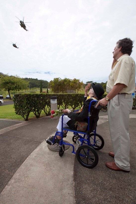 Virginia Ireland, the widow of retired Col. Julius Wirth "Buck" Ireland, and her son, Michael, look on as two CH-53D Sea Stallion helicopters from Marine Heavy Helicopter Squadron 463 perform an aerial fly-over, honoring the colonel before his funeral at the Hawaii State Veterans Cemetery in Kaneohe, Hawaii, Aug. 9. The late Col. Ireland, a Marine F4U Corsair ace pilot credited with shooting down six enemy planes during aerial combat in World War II, earned three Distinguished Flying Crosses, 10 Air Medals, and a Letter of Commendation with Combat "V" during the war. He flew combat missions in 1944 with Marine Fighter Squadron 211 in the Rabaul, Solomons, and Bismarck Archipelago Islands areas, and with VMF-233 in the Ryukyus. After flying jets in the Korean War with VMF-324, he commanded the Marine Helicopter Task Unit in Vietnam in 1962, operating under combat conditions in Soc Trang and Da Nang. Ireland retired in February 1967 after 28 years of military service.