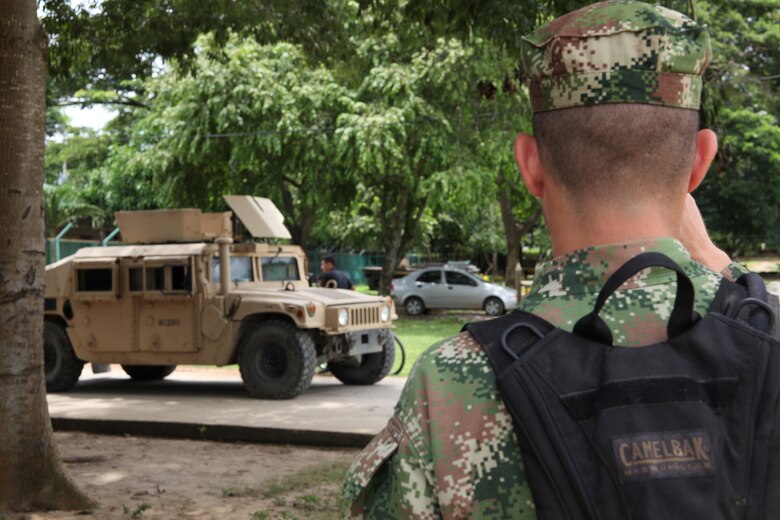 A Colombian Marine watches as U.S. Marines with Company A, 2nd Assault Amphibian Battalion, Ground Combat Element of Special-Purpose Marine Air-Ground Task Force Continuing Promise 2010, convoy Humvees to stage their vehicles and gear at a Colombian Marine Corps Training Base Covenas in Colombia, Aug. 10, 2010, in preparation for subject matter expert exchanges with Colombian Marines. The mission of CP10 is to conduct civil-military operations including subject matter expert exchanges, humanitarian civic assistance and disaster relief to partner nations to the Caribbean, Central and South America. (Marine Corps photo by Cpl. Alicia R. Giron)