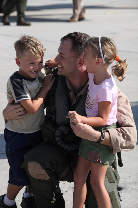 Capt. Trevor J. Felter, AV-8B Harrier pilot with Marine Attack Squadron 223, hugs his son and daughter, Aug. 10. VMA-223 was deployed with the 24th Marine Expeditionary Unit for seven months. ::r::::n::“Every moment of this is wonderful,” said Felters wife Jessica of her husband’s return.::r::::n::