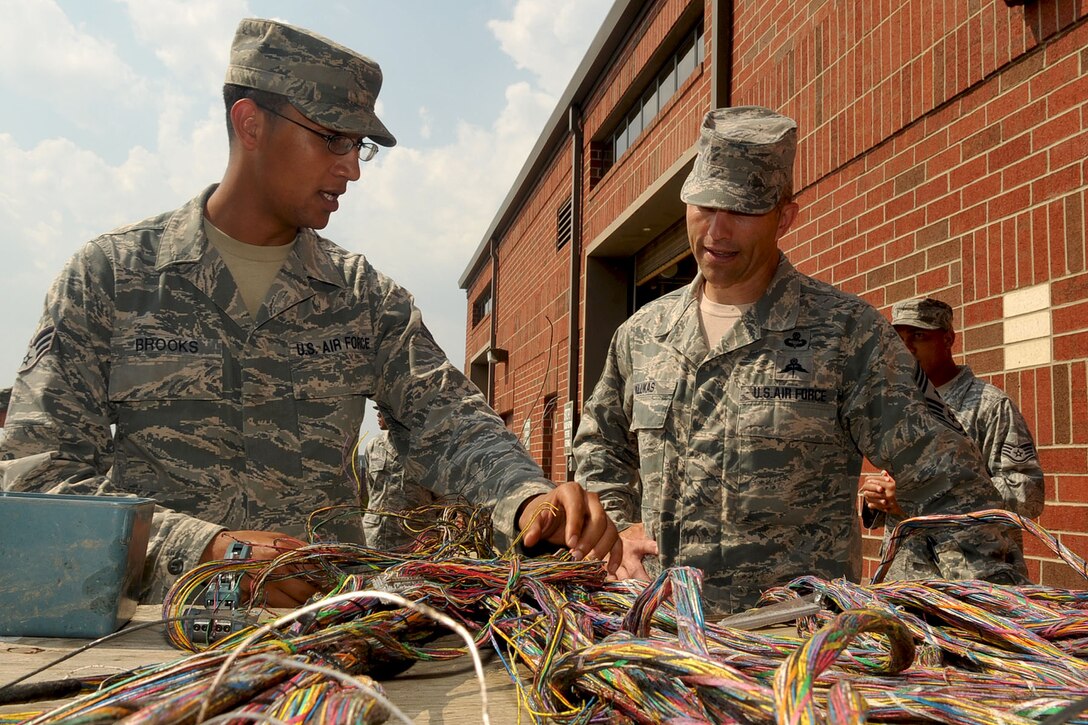 LANGLEY AIR FORCE BASE, Va -- Senior Airman Nathan Brooks, 633d Communications Squadron cable/maintenance systems technician, shows Air Combat Command Chief Master Sgt. Martin Klukas how to splice copper telephone cable during a base tour Aug. 10. Chief Klukas toured the base Aug. 9 and 10, interacting with the Airmen of all squadrons to better understand their work force and needs. (U.S. Air Force photo/Staff Sgt. Ashley Hawkins)(RELEASED)