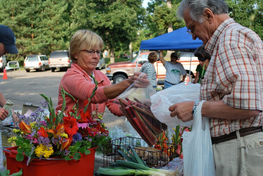 MINOT, N.D. -- Paulette Dailey, vendor at the Minot Farmer’s Market in Oak Park, assists a customer with his rhubarb purchase here Aug. 5. Dailey has been selling produce at the market for eight years. She is also the executive director of the Minot Symphony Orchestra. (U.S. Air Force photo by 1st Lt. Kidron B Farnell)