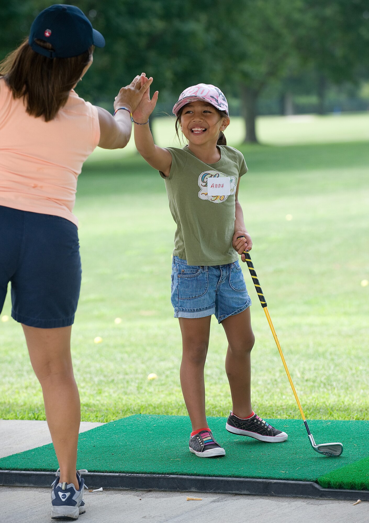 Anna Leah Blas, five, gives a high-five to Charma Bell, First Tee of Delaware coach, after hitting a great shot on the driving range July 28, 2010. The First Tee of Delaware program goal is to help instill a sense of confidence, integrity and sportsmanship in the children it teaches. (U.S. Air Force photo by Jason Minto/Released)