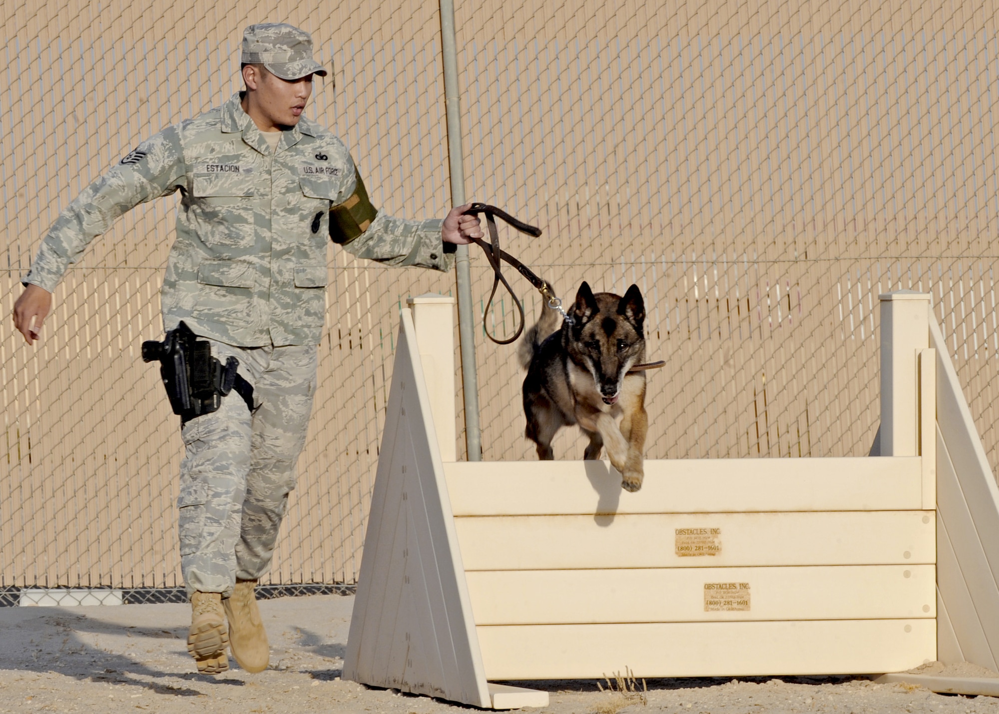 Staff Sgt. Lino Estacion takes his military working dog, Gabe, through an obstacle course as part of a routine training and exercise program July 27, 2010, in Southwest Asia. Sergeant Estacion is a dog handler with the 386th Expeditionary Security Forces Squadron. (U.S. Air Force photo/Senior Airman Laura Turner)