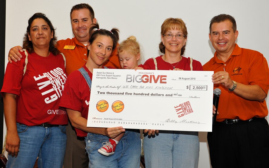 HOLLOMAN AIR FORCE BASE, N.M.  -- Members from the Big Give team, We Kare 4 Kids Kingdom, pose for a group photo after winning the small team Big Give Award at the Desert Sands Enlisted Club, Aug. 6, 2010. The team won $2,500 sponsored by Desert Sun Motors and also won the People's Choice Award -- $500 sponsored by the Otero Federal Credit Union. Their project was to help clean-up the children's recreational park, Kid's Kingdom, by sanding and repainting the playground and picnic tables, filling in holes, relaying tiles and cinder block caps, and moving 35 tons of mulch. (U.S. Air Force photo by Senior Airman Veronica Stamps / Released)