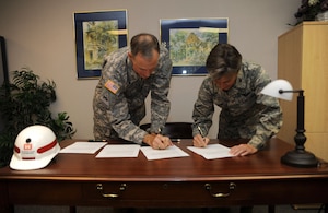 U.S. Army Lt. Col. Jason Kirk and U.S. Air Force Col. Martha Meeker sign a memorandum of agreement between Joint Base Charleston and the United States Army Corps of Engineers, Charleston District, at the Airman and Family Readiness Center Aug. 10, 2010, on Joint Base Charleston, S.C. On average, the Army unit has six to eight Department of Defense civilian employees deployed in support of overseas contingency operations at any one time. These employees and their families will benefit from pre- and post-deployment counseling the MOA now provides. Additionally, those returning from deployment and their families will benefit from re-integration classes. Services to be provided also include developing wills and powers of attorney for the Army personnel at JB CHS. Colonel Meeker is the commander of JB CHS and Colonel Kirk is the commander of U.S. Army Engineer District, Charleston. (U.S. Air Force Photo/Airman 1st Class Lauren Main)