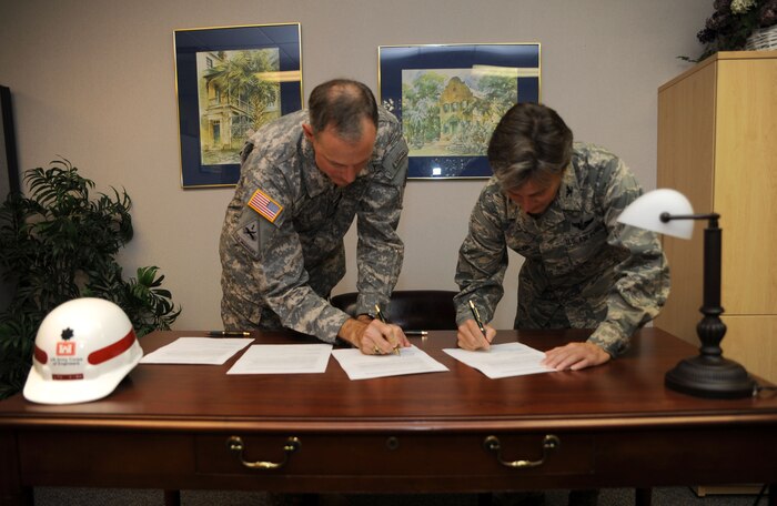 U.S. Army Lt. Col. Jason Kirk and U.S. Air Force Col. Martha Meeker sign a memorandum of agreement between Joint Base Charleston and the United States Army Corps of Engineers, Charleston District, at the Airman and Family Readiness Center Aug. 10, 2010, on Joint Base Charleston, S.C. On average, the Army unit has six to eight Department of Defense civilian employees deployed in support of overseas contingency operations at any one time. These employees and their families will benefit from pre- and post-deployment counseling the MOA now provides. Additionally, those returning from deployment and their families will benefit from re-integration classes. Services to be provided also include developing wills and powers of attorney for the Army personnel at JB CHS. Colonel Meeker is the commander of JB CHS and Colonel Kirk is the commander of U.S. Army Engineer District, Charleston. (U.S. Air Force Photo/Airman 1st Class Lauren Main)