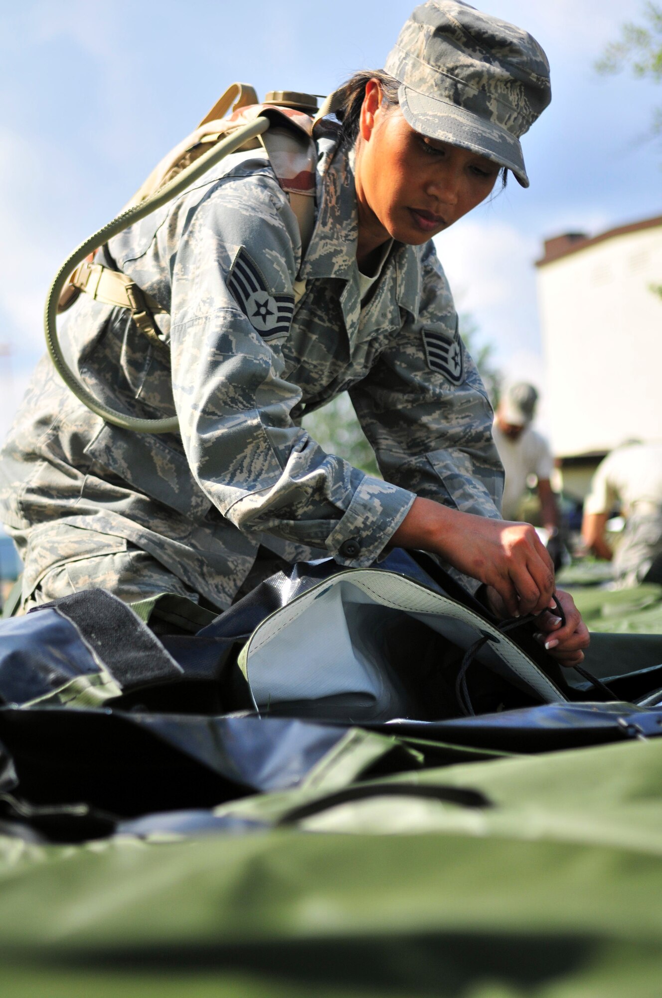 86th Medical Group technician Staff Sgt. Glenda Castillo ties strings used to connect sides of a tent designed to house up to ten patients during set up of the Ramstein Mobile Aeromedical Staging Facility training site, here, Aug. 2-6. Each member of the MASF is part of an elite group of volunteers who man the MASF positions on a two-year basis, knowing as combatant commander enablers they are expected to deploy with only 24 hours notice. (U.S. Air Force photo by Tech. Sgt. Michael Voss)
