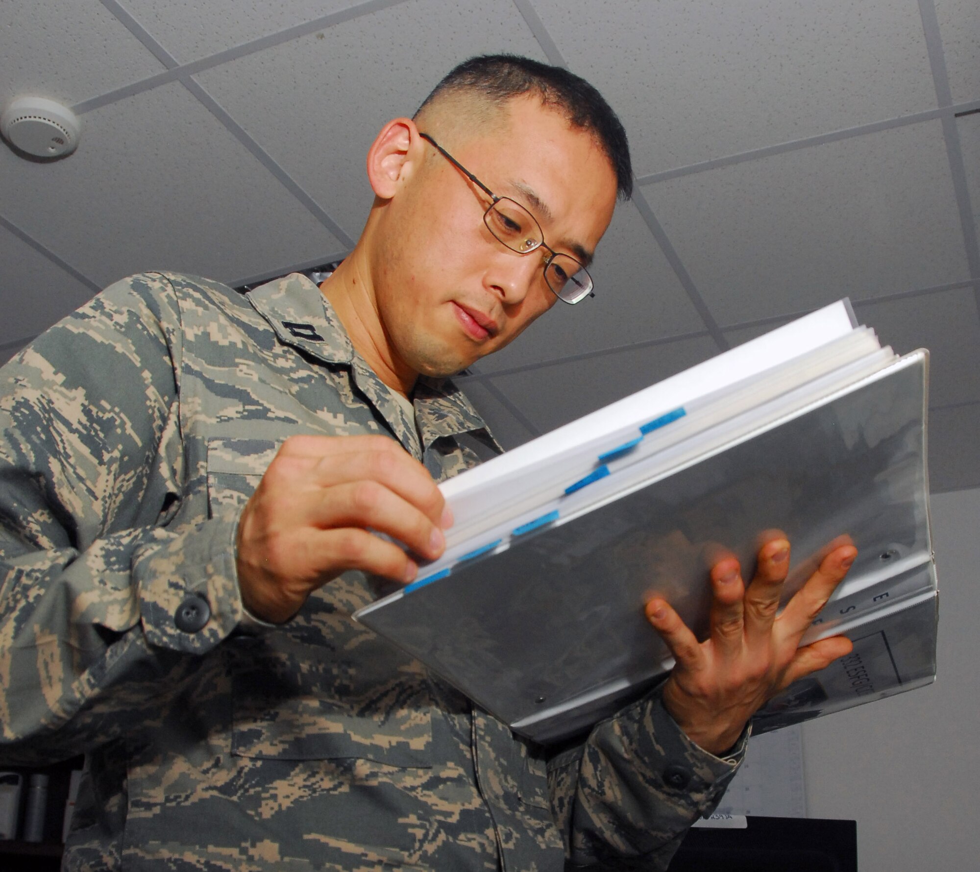 Capt. Ted Kim, 332nd Expeditionary Security Forces Group executive officer, flips through a continuity binder ensuring that the checklists and rosters are up to date Aug 6, 2010, Joint Base Balad, Iraq. It is imperative that every policy letter, checklist, rosters, and phone lists are up to date at all times in case of an emergency. Capt. Kim is a native of Irvine, Calif., deployed from Wright-Patterson Air Force Base, Ohio. (U.S. Air Force photo/Senior Airman Marianne E. Lane)