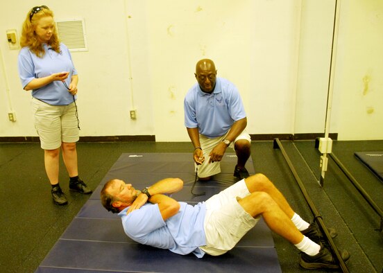 100809-F-6593P-002 SHAW AIR FORCE BASE, S.C. -- Pamela Tolliver and Mark Turner watch Rob Bahre, all members of the Fitness Assesment Cell, as he does sit-ups to demonstrate what they will be doing during the fitness assesment test August 5, 2010. All Airman now go through the  FAC as part of the standarization that has taken place for the new fitness test that began July 1, 2010.