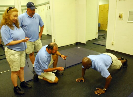 100809-F-6593P-002 SHAW AIR FORCE BASE, S.C. -- Pamela Tolliver, David Gherke and Rob Bahre watch Mark Turner, all members of the Fitness Assesment Cell, as he does push-ups to demonstrate what they will be doing during the fitness assesment test August 5, 2010. All Airman now go through the  FAC as part of the standarization that has taken place for the fitness test.