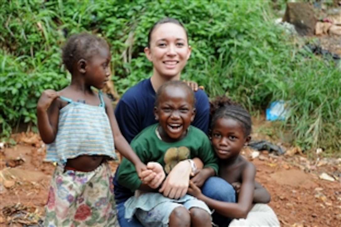 U.S. Coast Guard Seaman Rebekah Runner takes a moment to pose after some play time with three little girls from the Freetown Christian Faith Rescue Orphanage in Freetown, Sierra Leone, Aug. 9, 2010. Runner and other crewmembers from the Coast Guard Cutter Mohawk spent the day building a kitchen and repairing a shower at the orphanage. 