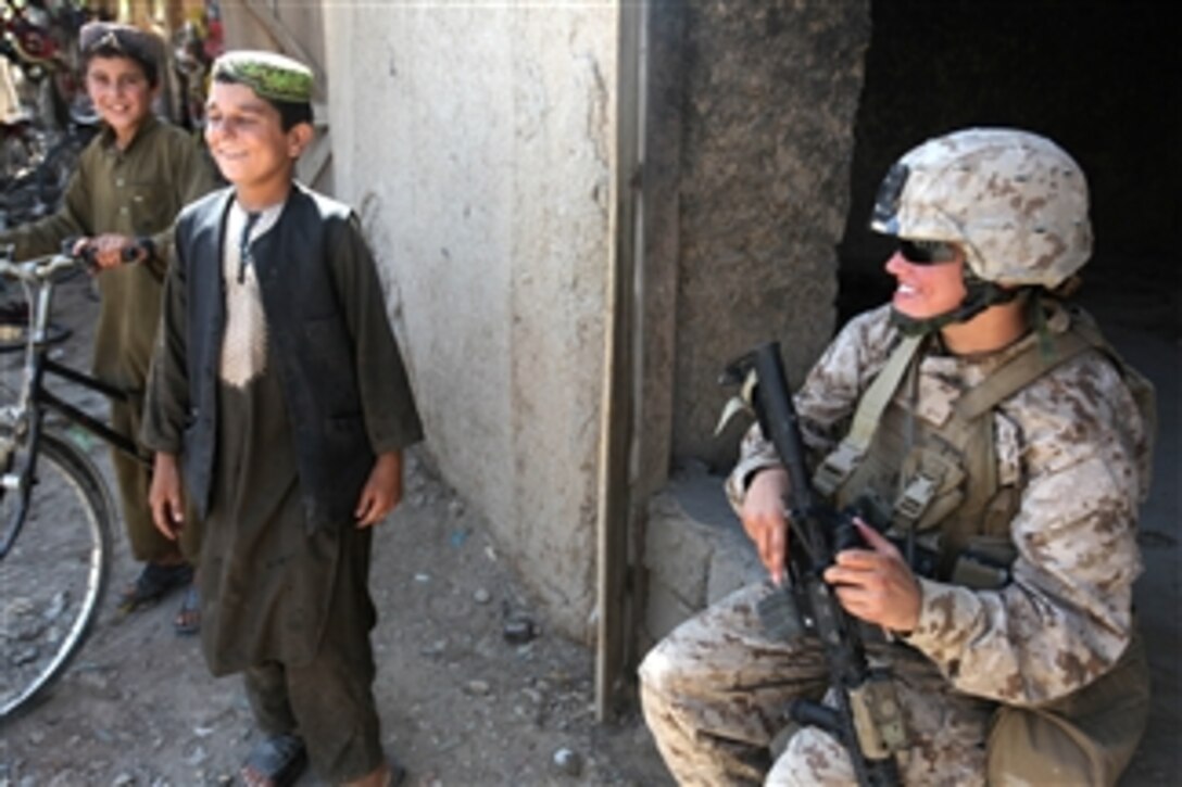 U.S. Marine Cpl. Mary E. Walls (right), an ammunition technician with a female engagement team, laughs with Afghan children during a patrol with 1st Battalion, 2nd Marine Regiment in Musa Qa'leh, Afghanistan, on Aug. 6, 2010.  Walls and other female engagement team members patrolled local compounds around the district center to establish relationships with local people and talk with the women of the area in support of the International Security Assistance Force.  