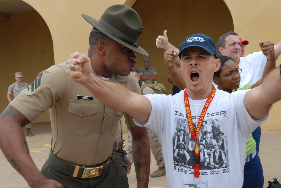 Sgt. Brandon A. Small, drill instructor, 1st Recruit Training Battalion, Recruit Training Regiment, sternly instructs Terry Coker, geography teacher, Montgomery High school, Montgomery, Texas, to stand still and get into the position commanded on the depot’s yellow footprints, Aug. 10.