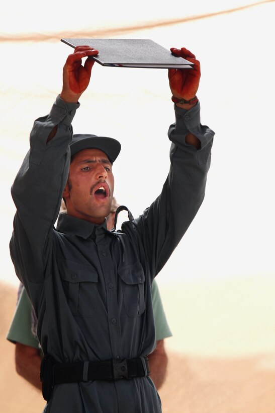 A newly-graduated police officer from Joint Security Academy Southwest class 2007-07 holds up his diploma during his graduation ceremony held at Camp Leatherneck, Afghanistan Aug. 11.