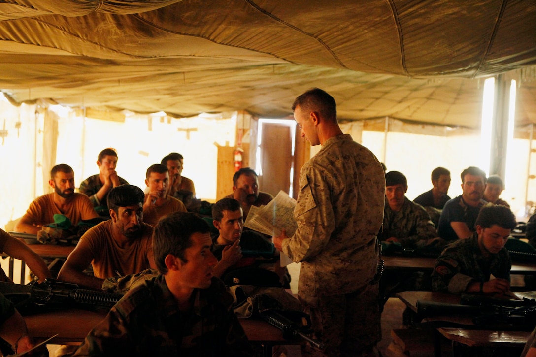First Lt. Alexander Livingston, the officer in charge of the NCO course, at the Joint Security Academy Southwest, distributes maps to Afghan National Army soldiers from the 215th Corps who are attending the NCO course, Aug. 11. Class members were tested using these individuals maps to confirm they retained the knowledge.