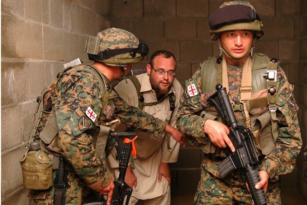Two Georgian soldiers capture a potential high-value-target individual in a building in a simulated Afghanistan village at the Joint Multinational Readiness Center here during their situational training exercise. The Republic of Georgia's 32nd Light Infantry Battalion is the second of four battalions to undergo training through the Georgia Deployment Program, a Marine Corps-led initiative designed to prepare the Georgians for their upcoming Afghanistan deployment in support of International Security Assistance Forces there.