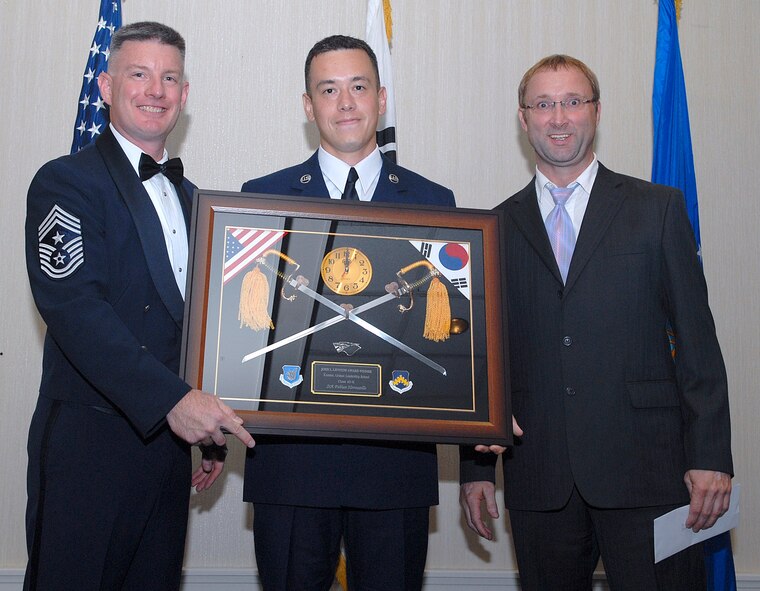 KUNSAN AIR BASE, Republic of Korea -- Chief Master Sgt. Stephen Ludwig, 7th Air Force command chief master sergeant, and Brian Boyle, University of Maryland representative, present Staff Sgt. Fabian Hermosillo, 8th Aircraft Maintenance Squadron, with the John L. Levitow Award during the Kunsan Airman Leadership School Class 10-K graduation here Aug. 6. The class was the first at Kunsan in six years. (U.S. Air Force photo/Senior Airman Roy Lynch)