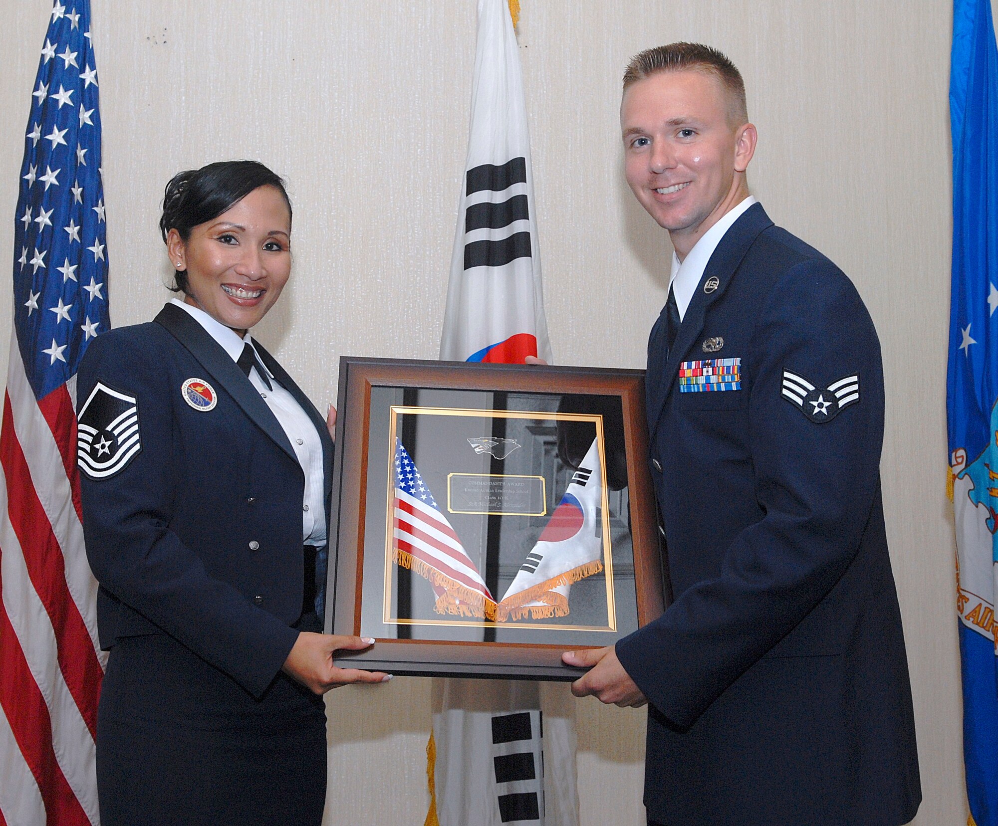 KUNSAN AIR BASE, Republic of Korea -- Master Sgt. Maryann Navarro-Davis, Kunsan Airman Leadership School Class 10-K commandant and instructor, presents Senior Airman Michael Alexander, 8th Aircraft Maintenance Squadron, with the Commandant Award during the ALS Class 10-K graduation here Aug. 6. Airman Alexander was also named a Distinguished Graduate. The class was the first at Kunsan in six years. (U.S. Air Force photo/Senior Airman Roy Lynch)