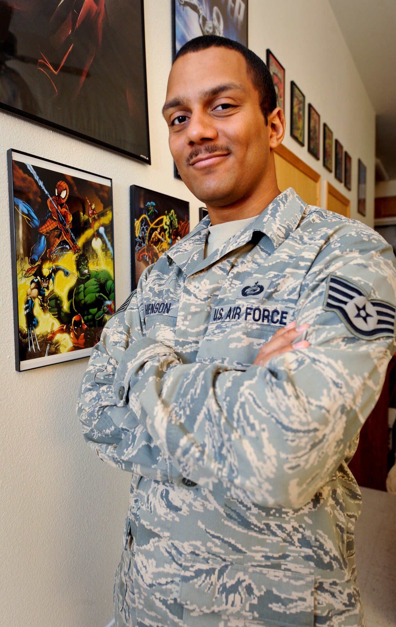 MINOT AIR FORCE BASE, N.D. -- Staff Sgt. Eric Henson, 5th Force Support Squadron base personnel reliability program monitor, poses in front of some of his first pieces of comic art in his home here Aug. 11. Sergeant Henson has been a comic artist since he was five years old when his father gave him a “Silver Surfer” comic book. (U.S. Air Force photo by Senior Airman Benjamin Stratton)