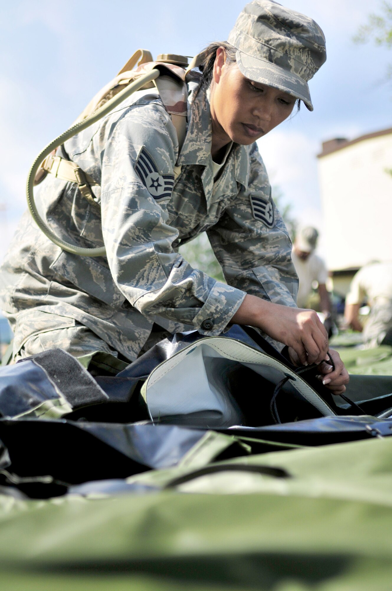Staff Sgt. Glenda Castillo ties strings used to connect sides of a tent designed to house up to ten patients during set up of the Ramstein Mobile Aeromedical Staging Facility training site Aug. 2, 2010, at Ramstein Air Base, Germany. Each member of the MASF is part of a group of volunteers who man the MASF positions on a two-year basis, knowing as combatant commander enablers they are expected to deploy with only 24 hours notice. Sergeant Castillo is an 86th Medical Group technician. (U.S. Air Force photo/Tech. Sgt. Michael Voss)