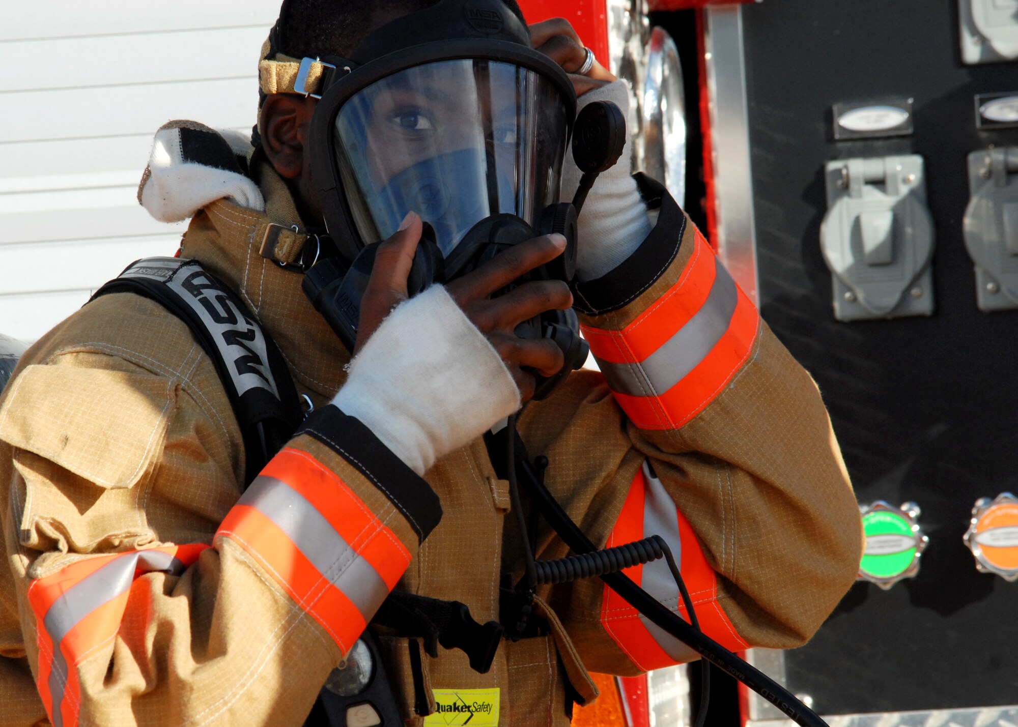 Airman 1st Class DeMichael Overstreet, 96th Civil Engineer Squadron, dons a respirator mask before moving to put out a simulated engine fire during Nuclear Accident Response Exercise Aug. 11 at Eglin Air Force Base, Fla.  This exercise assessed the ability of base personnel to support a request from Department of Energy “Safe Haven” and react to an emergency response to a major accident. In the scenario, while securing the vehicles from a DoE convoy on base, the DoE truck experienced an engine fire and two DoE personnel suffered severe burns while trying to extinguish the fire. Emergency personnel responded to the situation, secured the scene, transported the victims and put out the fire.  (U.S. Air Force photo/Samuel King Jr.)
