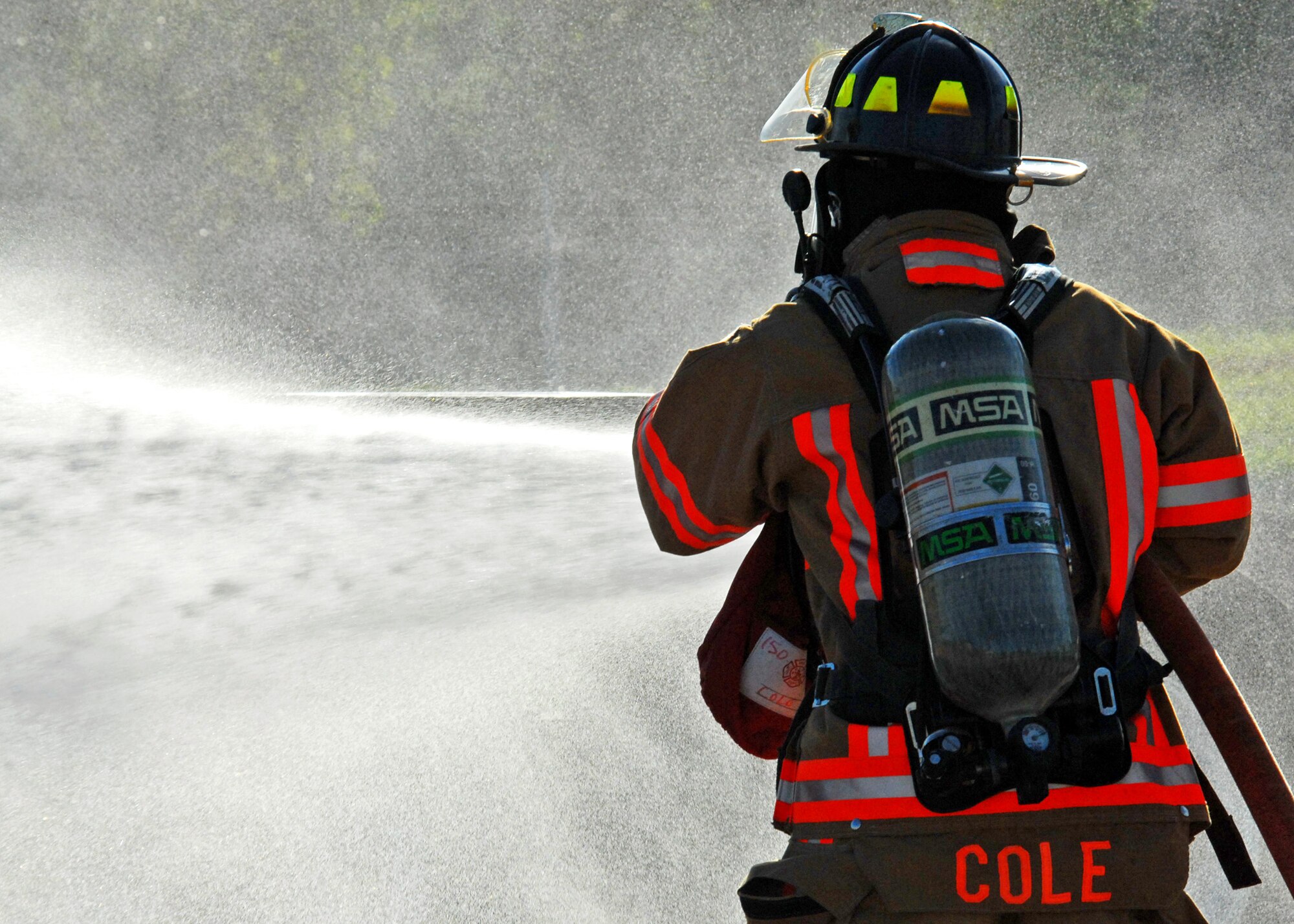 Rickie Cole, 96th Civil Engineer Squadron, douses the simulated truck fire during Nuclear Accident Response Exercise Aug. 11 at Eglin Air Force Base, Fla.  This exercise assessed the ability of base personnel to support a request from Department of Energy  and respond to a major accident. In the scenario, while securing the vehicles from a DoE convoy, the DoE truck experienced an engine fire and two DoE personnel suffered severe burns while trying to extinguish the fire. Emergency personnel responded to the situation, secured the scene, transported the victims and put out the fire.  (U.S. Air Force photo/Samuel King Jr.)