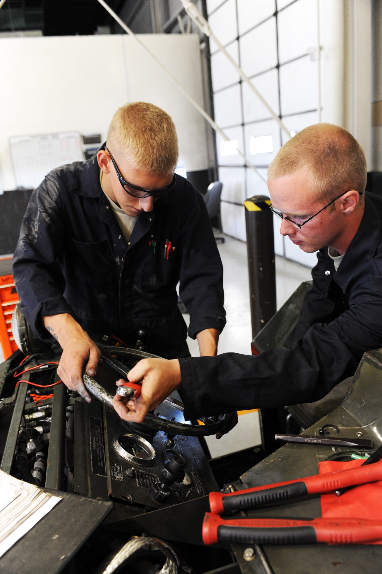 MINOT AIR FORCE BASE, N.D. -- Airmans 1st Class Jarrod Sonnes and Zachery Schwaigert, both 5th Maintenance Squadron aerospace ground equipment technicians, repair a bomb loader here Aug. 6. AGE supports the 5th Bomb Wing mission by repairing defective equipment used on the B-52H Stratofortress. (U.S. Air Force photo by Airman 1st Class Aaron-Forrest Wainwright)
