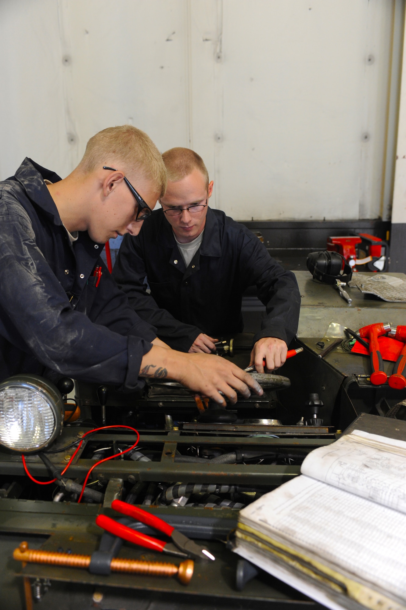MINOT AIR FORCE BASE, N.D. -- Airmans 1st Class Jarrod Sonnes and Zachery Schwaigert, both 5th Maintenance Squadron aerospace ground equipment technicians, repair a bomb loader here Aug. 6. AGE supports the 5th Bomb Wing mission by repairing defective equipment used on the B-52H Stratofortress. (U.S. Air Force photo by Airman 1st Class Aaron-Forrest Wainwright)