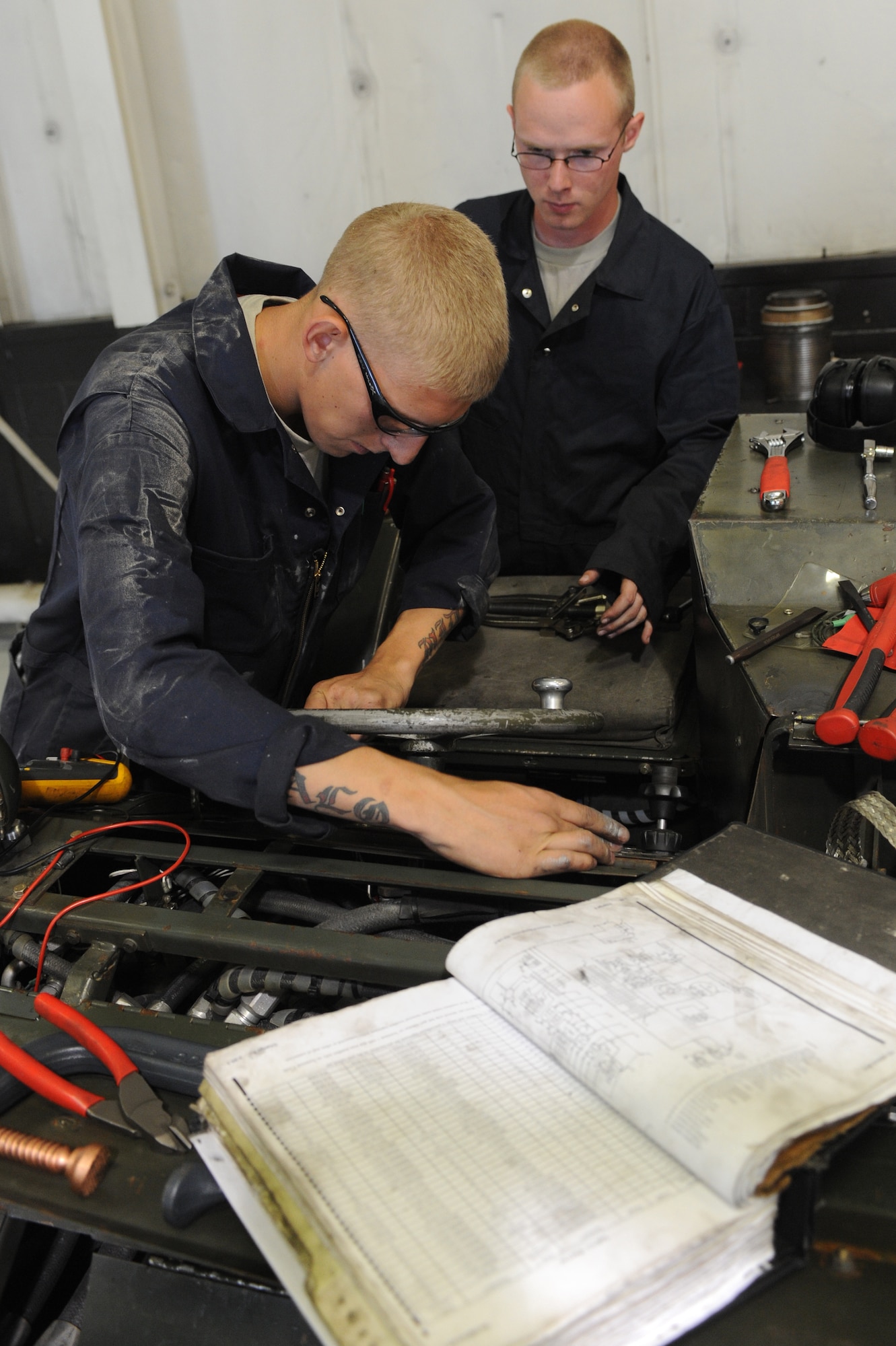 MINOT AIR FORCE BASE, N.D. -- Airmans 1st Class Jarrod Sonnes and Zachery Schwaigert, both 5th Maintenance Squadron aerospace ground equipment technicians, repair a bomb loader here Aug. 6. AGE supports the 5th Bomb Wing mission by repairing defective equipment used on the B-52H Stratofortress. (U.S. Air Force photo by Airman 1st Class Aaron-Forrest Wainwright)