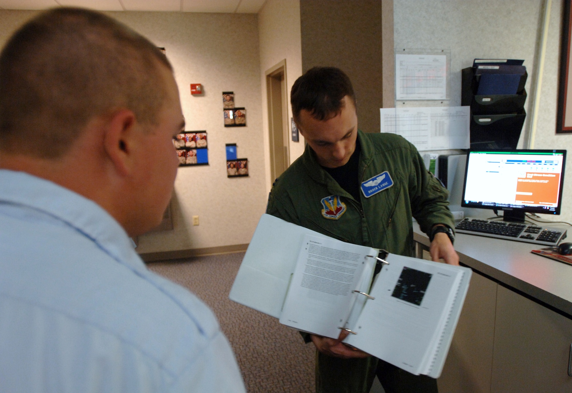 LANGLEY AIR FORCE BASE, Va. -- Capt. Brock Lange, a 94th Fighter Squadron pilot (right), explains portions of an F-22 Raptor pre-flight manual to Cadet Sean Chantal, a Menchville High School Air Force Junior Reserve Officer Training Corps cadet, at the 94 FS operations desk during “Shadow Day” Aug. 10. The event allowed more than 60 Hampton Roads-area cadets the opportunity to see the Air Force mission in action. (U.S. Air Force photo/Airman 1st Class Jason J. Brown)