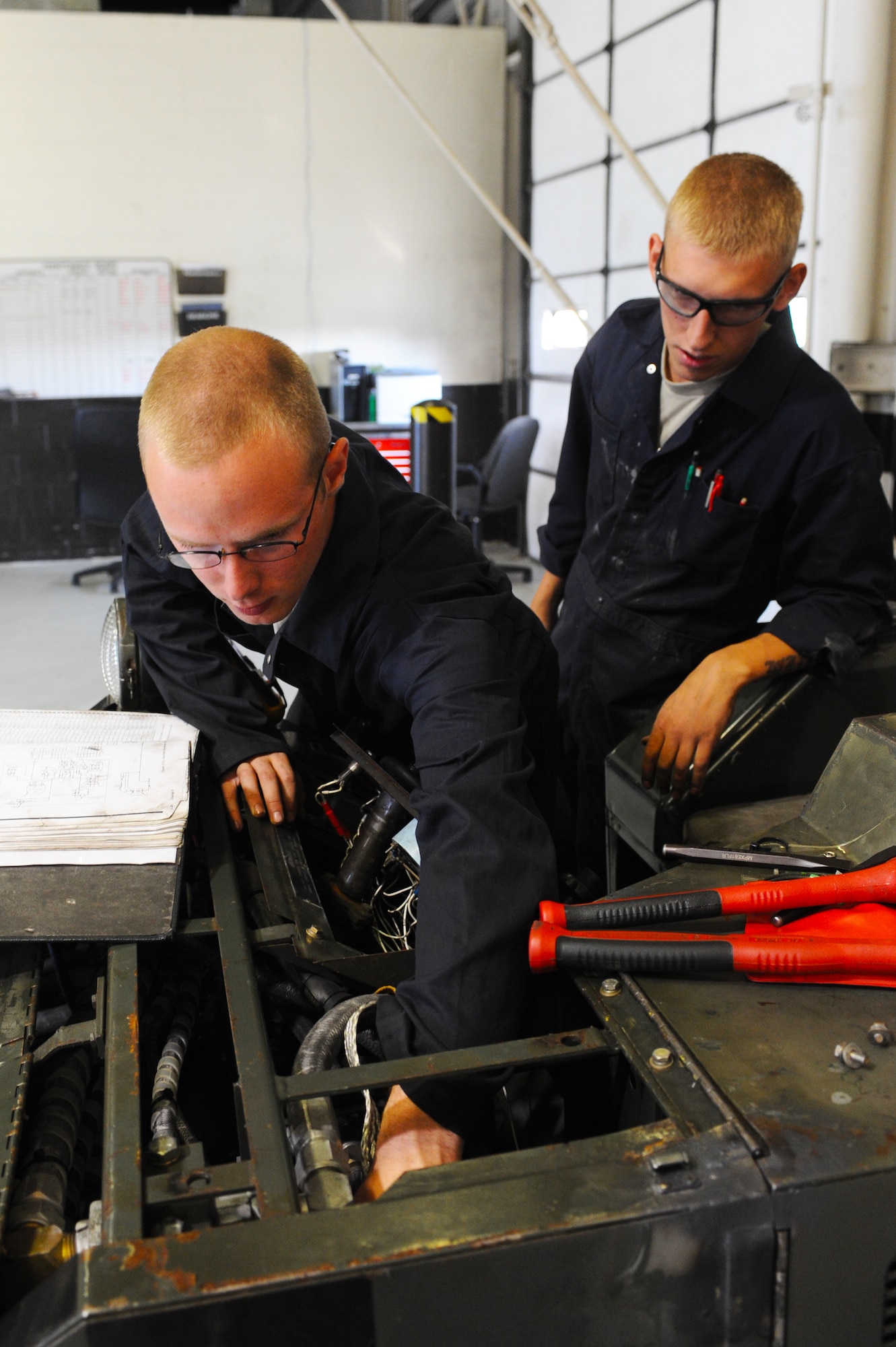 MINOT AIR FORCE BASE, N.D. -- Airmans 1st Class Jarrod Sonnes and Zachery Schwaigert, both 5th Maintenance Squadron aerospace ground equipment technicians, repair a bomb loader here Aug. 6. AGE supports the 5th Bomb Wing mission by repairing defective equipment used on the B-52H Stratofortress. (U.S. Air Force photo by Airman 1st Class Aaron-Forrest Wainwright)