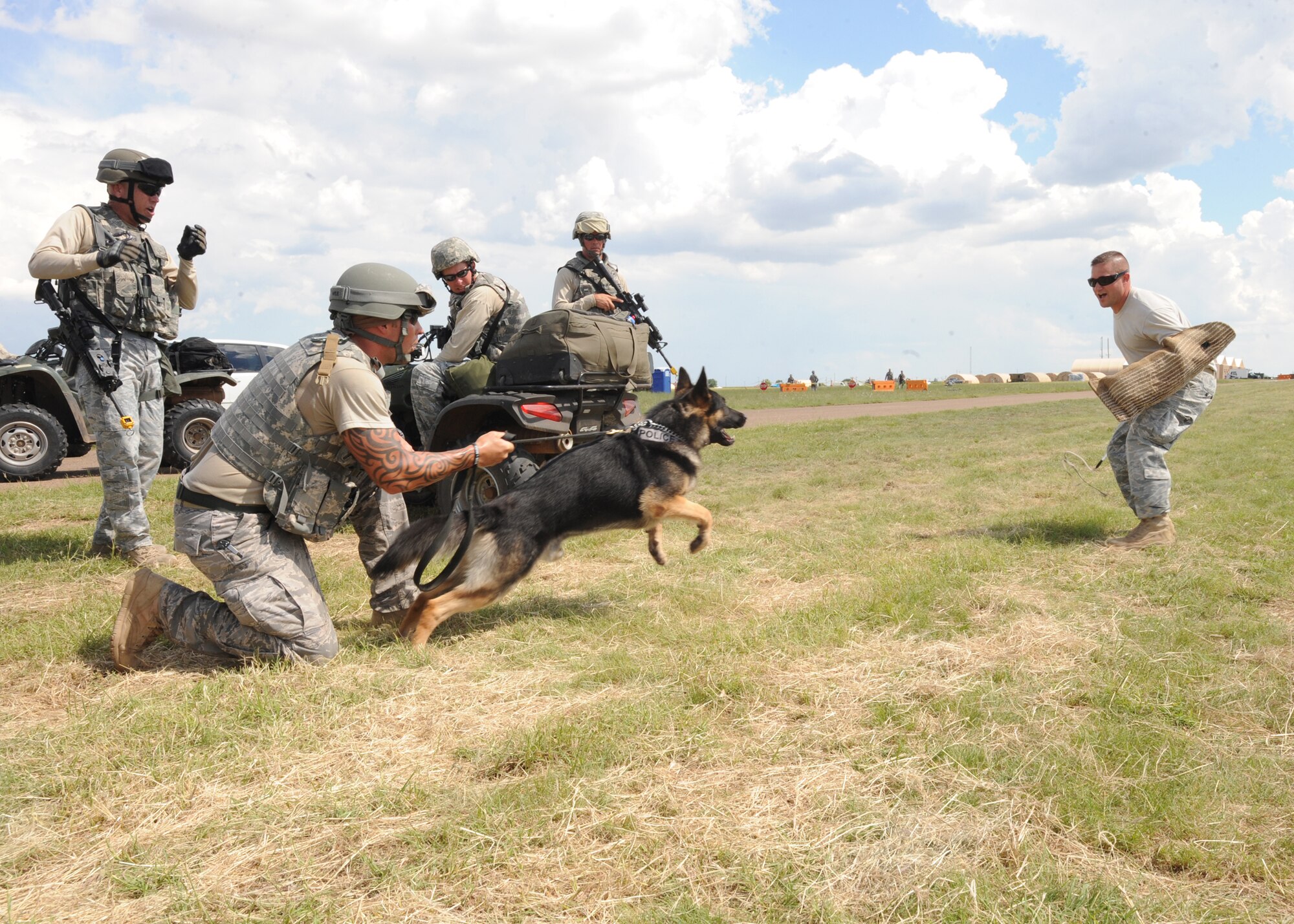 Staff Sgt. Adam Wylie, 27th Special Operations Security Forces Squadron, holds onto his trained military working dog, Jackson, just as Staff Sgt. David Emington, 27 SOSFS, takes off in a sprint Aug 10, 2010. Military working dogs are part of a unit specially trained in finding drugs, hunting and taking down adversaries. (U.S. Air Force photo by Airman 1st Class Maynelinne De La Cruz)
