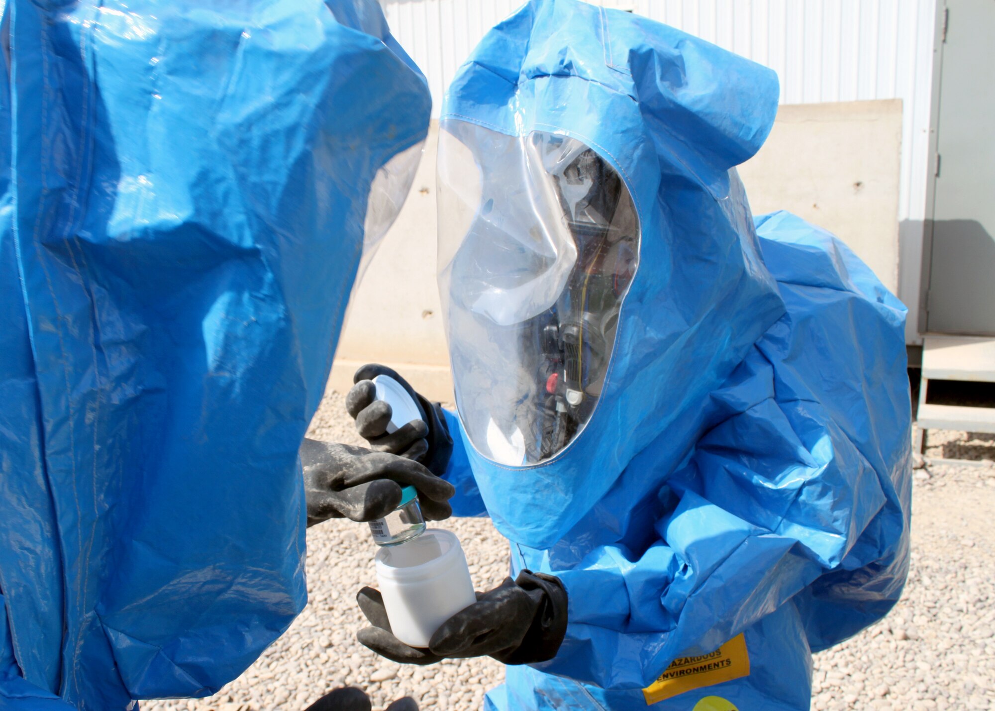 Senior Airmen Nathan Krajcirik (left) and Nadege James place a sample of an "unknown" powder into a protective container during training Aug. 3, 2010, at Joint Base Balad, Iraq. Emergency management Airmen can test a variety of potential chemical, biological or nuclear hazards in any form. Airmen Krajcirik and James are 332nd Civil Engineer Squadron Emergency Management Section technicians. (U.S. Air Force photo/Staff Sgt. Stacy Fowler)