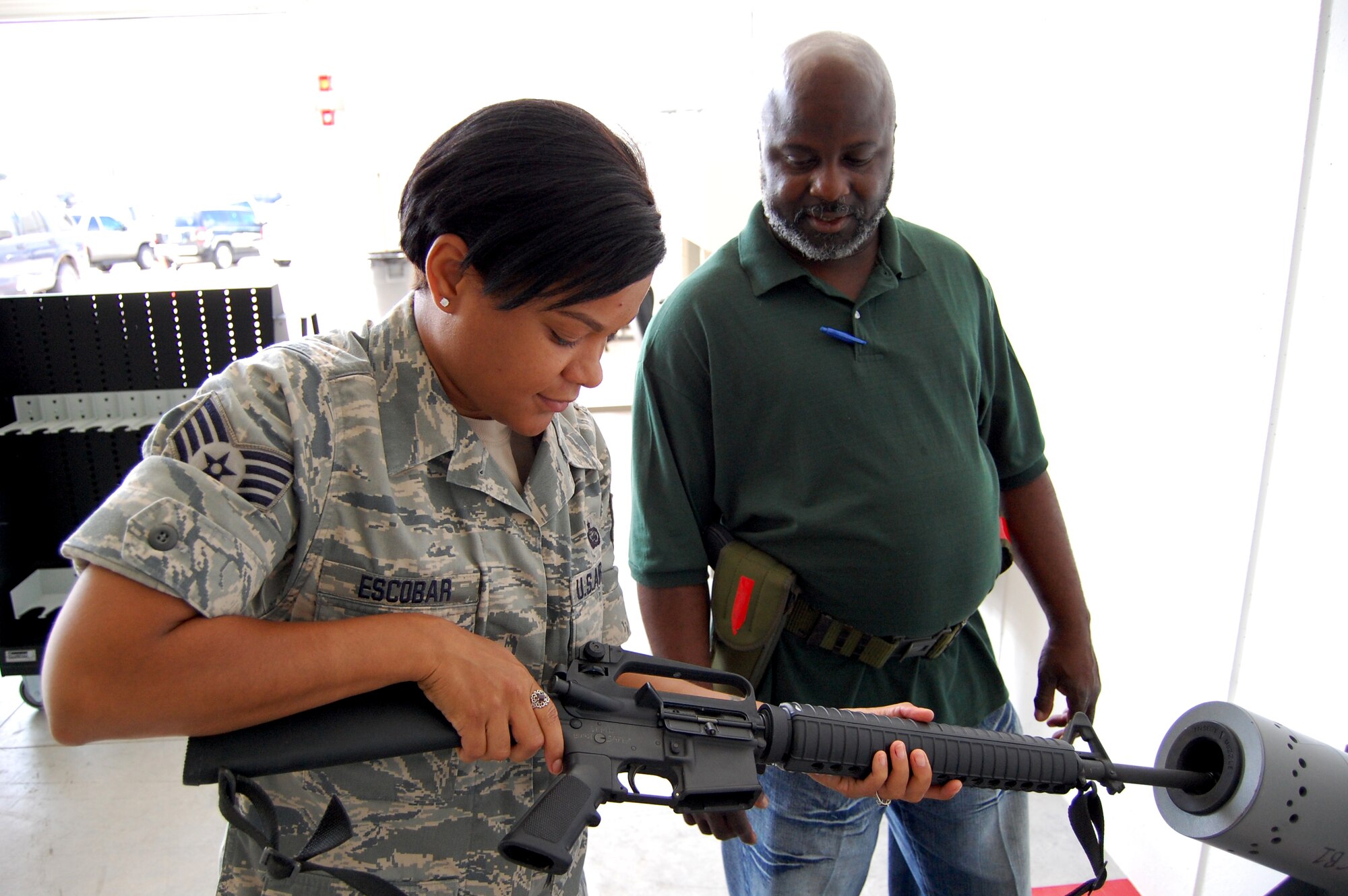 Jerry Lewis, 902nd Logistics Readiness Squadron, right, guides Staff Sgt. Jessica Escobar, Air Force Personnel Center Unit Deployment manager, through the M-16 rifle clearing procedures, at the 902nd Logistics Readiness Squadron Mobility Processing Center on Randolph Air Force Base Aug. 10. During exercise Joint Base San Antonio 10-08, more than 200 Airmen from different agencies on Randolph AFB participated in the two-day deployment exercise. (U.S. Air Force photo/Master Sgt. Paul Kilgallon)