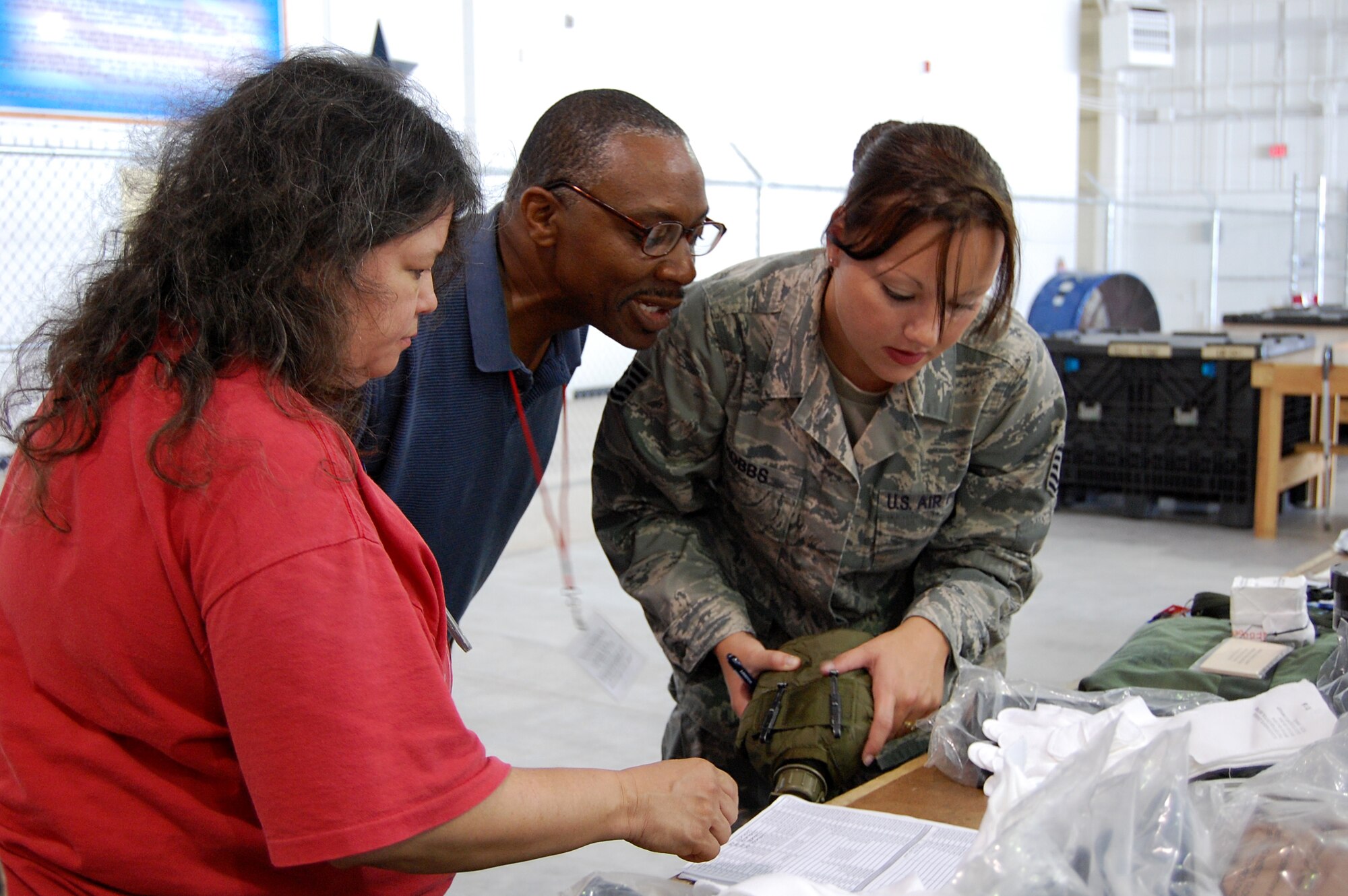 Kezia Hillary, 902nd Logistics Readiness Squadron, left, and Mr. Ken Hall, 902nd LRS, center, assist Tech. Sgt. Jessica Hobbs, Air Force Personnel Center, in inventorying her deployment equipment at the 902nd LRS Deployment Processing Center on Randolph Air Force Base Aug. 10. During exercise Joint Base San Antonio 10-08, more than 200 Airmen from different agencies on Randolph AFB participated in the two-day deployment exercise. (U.S. Air Force photo/Master Sgt. Paul Kilgallon)