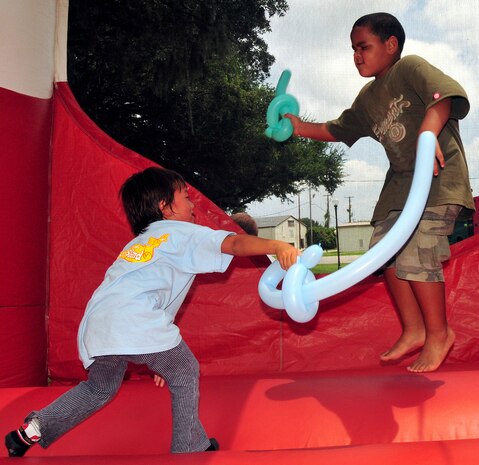 Max Williams lunges in to strike Eyfinn Ruffin with his balloon sword in an inflatable jump castle at the base picnic grounds Aug. 7, 2010, on Joint Base Charleston, S.C. As summer reading came to a close, base librarians said upcoming school season events were in store, such as a spooky story night in October and a holiday classics reading in December. Max is the son of 1st Lt. Kipp Williams, 373rd Training Squadron commander, and Eyfinn is the son of Robert Ruffin who is an Air Force retiree. (U.S. Air Force photo/Staff Sgt. Daniel Bowles)
