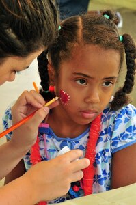 Jadyn Gamble stops by the face painting table for a sparkling heart touchup by Laverne Morris, a local vounteer, during the base library's summer reading finale at the base picnic grounds Aug. 7, 2010, on Joint Base Charleston, S.C. Jadyn attended the event with her brother Jacob, and together, with their father, Coast Guard Petty Officer 1st Class Roosevelt Gamble and mother Vicki Gamble, the family makes reading a top priority, said Mrs. Gamble, who is both a teacher and children's author. Petty Officer Gamble is with Naval Engineering Support Unit Charleston. (U.S. Air Force photo/Staff Sgt. Daniel Bowles)