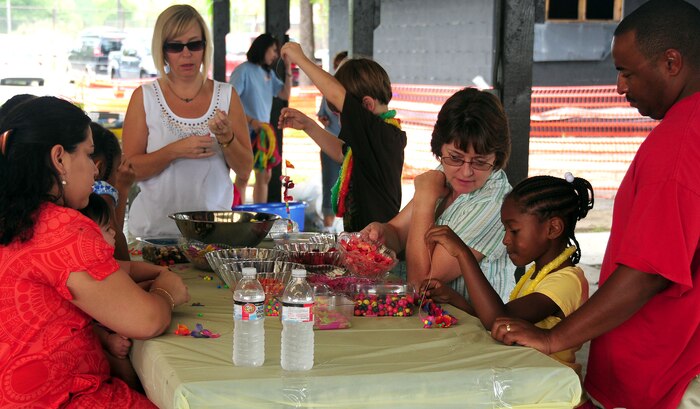 Parents, children and volunteers gather at the lei-making station at the base picnic grounds during the summer reading program finale hosted by the base library Aug. 7, 2010, on Joint Base Charleston, S.C. The finale celebrated all the hard work children put in to the seven-week program with fun, family, food, all centered around this year's theme of "Voyage to Book Island." Activities at the finale included face painting, hula hoops, play dough craft station, oversized basketball, a bubble station and jump castle. (U.S. Air Force photo/Staff Sgt. Daniel Bowles)