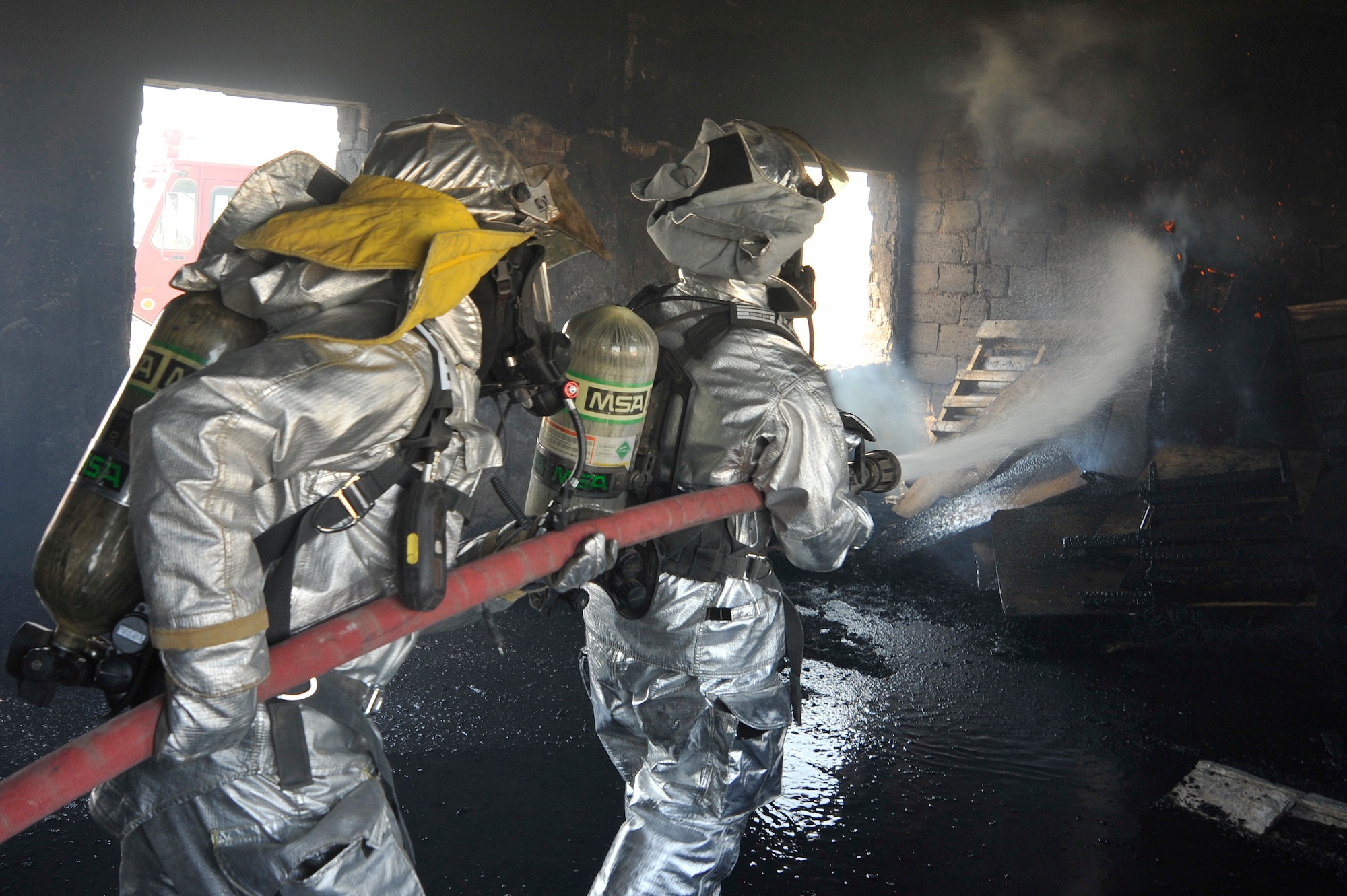 447th Expeditionary Civil Engineer Squadron firefighters extinguish a fire in a training room during live burn training, Aug. 9, 2010, at Baghdad International Airport, Iraq. Firefighters from the 447th ECES, BIAP and Iraqi air force, frequently train in structural firefighting, to improve their skills. ( U.S. Air Force photo by Senior Airman Perry Aston) (Released)